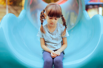 Sad Little Girl Sitting Alone in a Playground Slide. Timid anxious single child having none to play with
 - obrazy, fototapety, plakaty