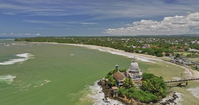 Matara Sri Lanka Aerial v1 cinematic drone fly around Parewi Duwa Temple on a rocky island capturing long stretch sandy beach and Kotuwegoda village town views - Shot with Mavic 3 Cine - April 2023