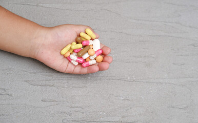 children's hands hold a lot of multi-colored drugs on a grey background
