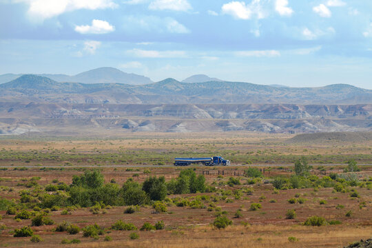 A lone tractor trailer travels through a western US landscape