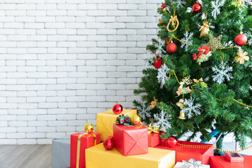 Beautiful Christmas tree was decorated by Christmas baubles as colorful Christmas glass ball, snowflakes, toys model and gift boxes was under Christmas tree with grey wall background and copy space - 653546970