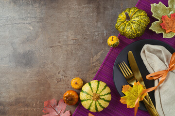Thanksgiving party concept with  plate, pumpkin and autumn leaves on dark background. Top view, flat lay