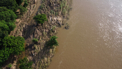Aerial view of water released from the drainage channel of the concrete dam is a way of overflowing water in the rainy season. Top view of turbid brown forest water flows from a dam in Thailand.
