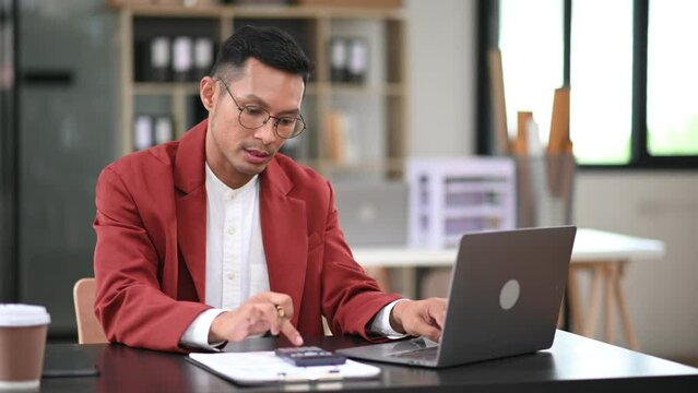 Asian business man executive manager looking at laptop watching online webinar training or having virtual meeting video conference doing market research working in office..