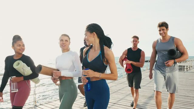 Tired group of people walk along sea after yoga training