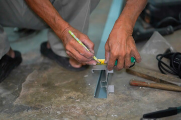 Closeup hands of builder using a pencil marks out the details before cutting aluminum lumber at...
