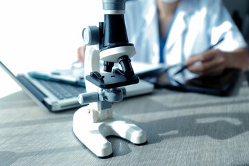 Young scientists conducting research investigations in a medical laboratory, a researcher in the foreground is using a microscope
