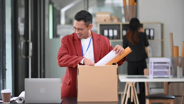 Happy and excited young Asian man office worker celebrating her resignation, carrying her personal stuff. leaving job, changing or company. in office