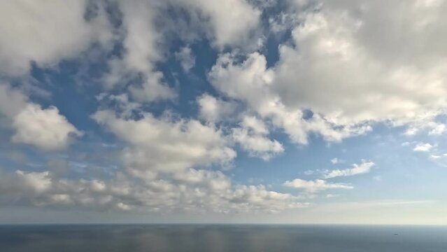 Timelapse fluffy Cumulus clouds moving on camera in bright sunset sky over calm sea. Abstract aerial nature summer ocean sea and sky view. Vacation, travel, holiday concept. Weather and Climate Change