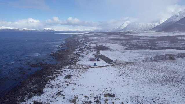 Aerial forwarding shot of grunnfor in Lofoten during winter with snow covered landscape and a snow storm