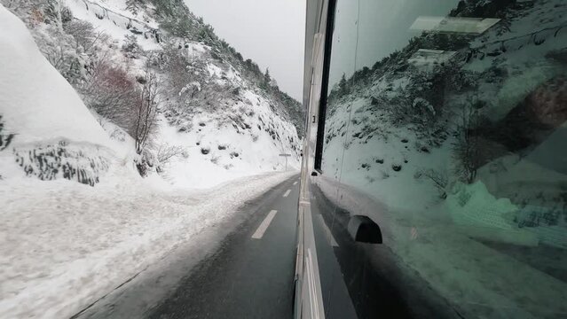 Vehicle van camper rv motorhome outside passenger window view traveling in snow winter roads with snowy mountains reflected on the glass. Concept of traveler and vacation. Vanlife lifestyle. Nature