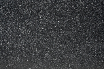 Fototapeta premium Black paper decorative background with silver sparkling glitter texture, shimmering in bright light. Space with stars styled concept background