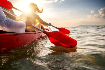 Foto op Plexiglas Happy young couple walks on kayak at sunset sea bay. Close up photo of paddles in water © cppzone