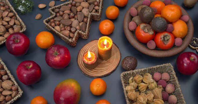 Healthy Christmas snacks: nuts and fruits on a table with two candles. Camera slide.