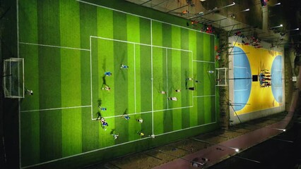 An aerial view of an evening sports ground with soccer and basketball fields, where children are practicing football and basketball.