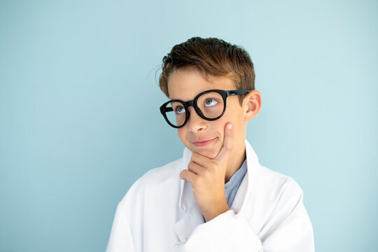 cool young male scientist with white coat and thick black glasses in front of blue background