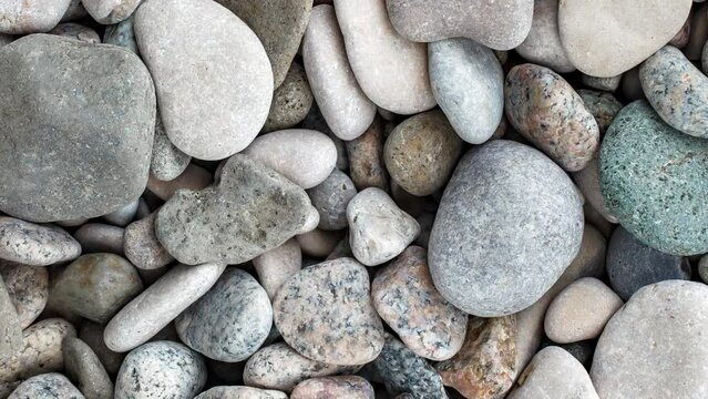 Pebbles, large round beach sea stones, rotating, turning, close-up macro, top view
