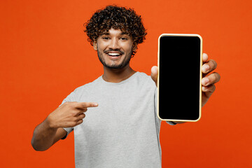 Young Indian man he wears t-shirt casual clothes hold in hand use point finger on mobile cell phone...