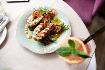 red fish dish, restaurant serving, table setting, dishes on a white tablecloth. food tasting. There are several pieces of fish on a white plate