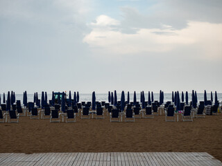 Closed beach parasol at empty seaside coast. Beach in Italy - 653587326