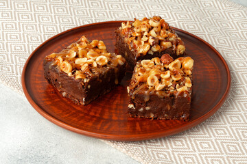 Brownie cake with nuts topping on plate close up