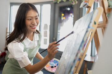 Asian woman is painting art. She is a professional artist. Watercolor artist is painting art on...