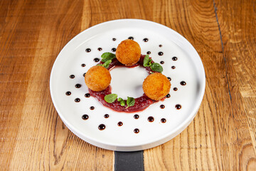 restaurant dish on a wooden table, cheese balls, cranberry sauce