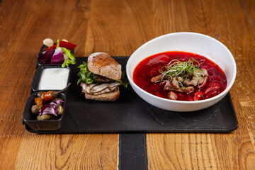 restaurant dish on a wooden table, first course, borscht, lard