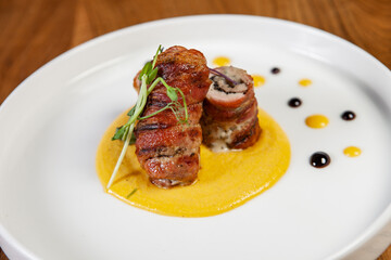 restaurant dish on a wooden table, chicken rolls in bacon