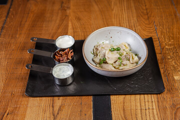 restaurant dish on a wooden table, dumplings, sour cream, bacon