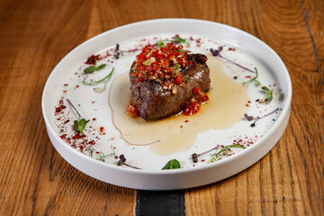 restaurant dish on a wooden table, steak, vegetables, sauce