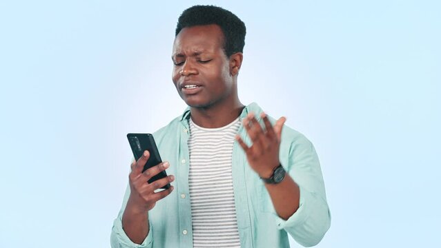 Phone, stress and black man in studio with cybersecurity problem, mistake or crisis on blue background. Smartphone, fail and African male model frustrated by glitch, phishing or social media hacker