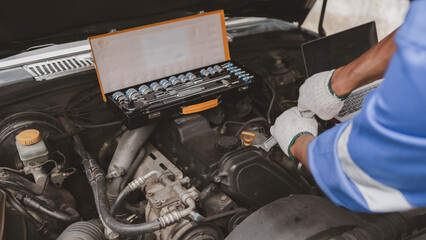 Car mechanic is inspecting the engine of a car coming in for repair at the center. Professional engine specialist, car repair, car breakdown. Car maintenance and repair concept.