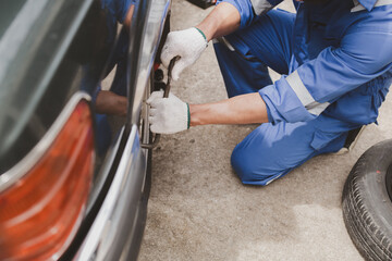 Car mechanic is inspecting tires and replacing worn tires through long hours of work, car repairs,...