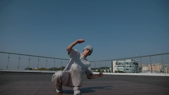 The guy coolly dances breakdance on the roof of the house. Slow motion shooting. A man dances an energetic athletic dance.
