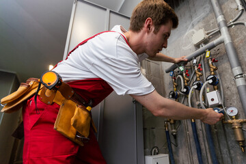maintenance - technician checking pressure meters for house heating system.