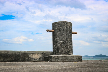 Concrete pillar for mooring ships on a pier. Bollard against the blue sky.