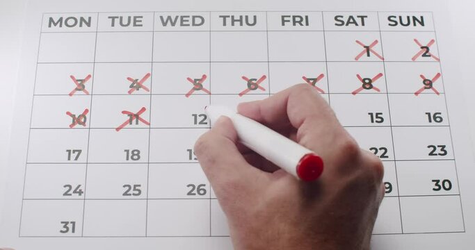 Man hand marking dates in month calendar with red cross. Person mark days in personal checklist. New habits tracker