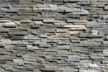 Stone cladding wall made of striped stacked slabs of natural gray and white rocks.  Panels for...