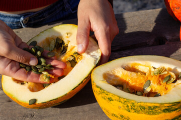a person divides a bare-seeded pumpkin into two parts with his hands and takes out the bare seeds
