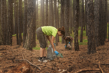 Eco-Friendly Cleanup in the Forest: A sunlit summer backdrop highlights an adult woman and man...