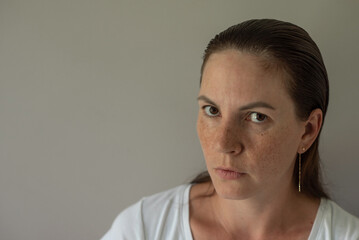 A judgmental look. A female portrait depicting doubt and condemnation on a gray background.