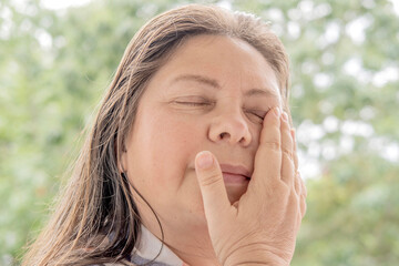 close-up of mature charismatic woman 50 years holding hand over eye, eye pain treated medical...