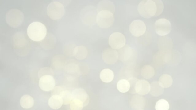 Abstract blurred glowing golden lights rotate in slow motion. White shining bokeh background. Christmas and New Year