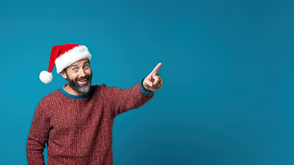 Fototapeta na wymiar Man in his 40s with winter Christmas clothes and accessory pointing on blue background.