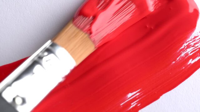 Close-up of artist holding paint brush and drawing oil, acrylic or  gouache painting. Fill red color on canvas. Painting red strokes on canvas
