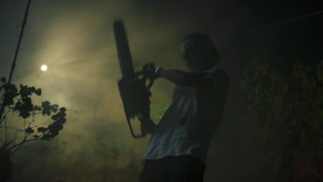 Silhouette Of A Crazy Man Fight With Chainsaw In Night Forest