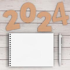 Cardstock Numbers 2024 Happy New Year Sign near White Spiral Paper Cover Notebook with Pen over table. 3d Rendering