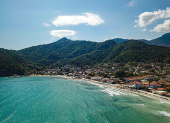 Aerial drone view from the Aegean sea of the shore of the Golden Beach area in Thassos Island , Greece , showing the resorts and hotels , tourist accommodation , the pure white sand shore