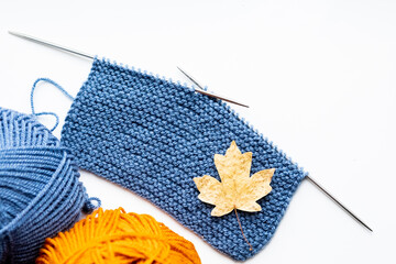 A piece of cloth knitted with blue threads and two balls of blue and yellow threads on a white background 